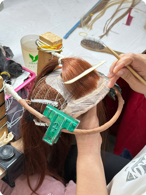 SHY Hair craftsperson working on a custom wig cap secured to a head mold at the workbench